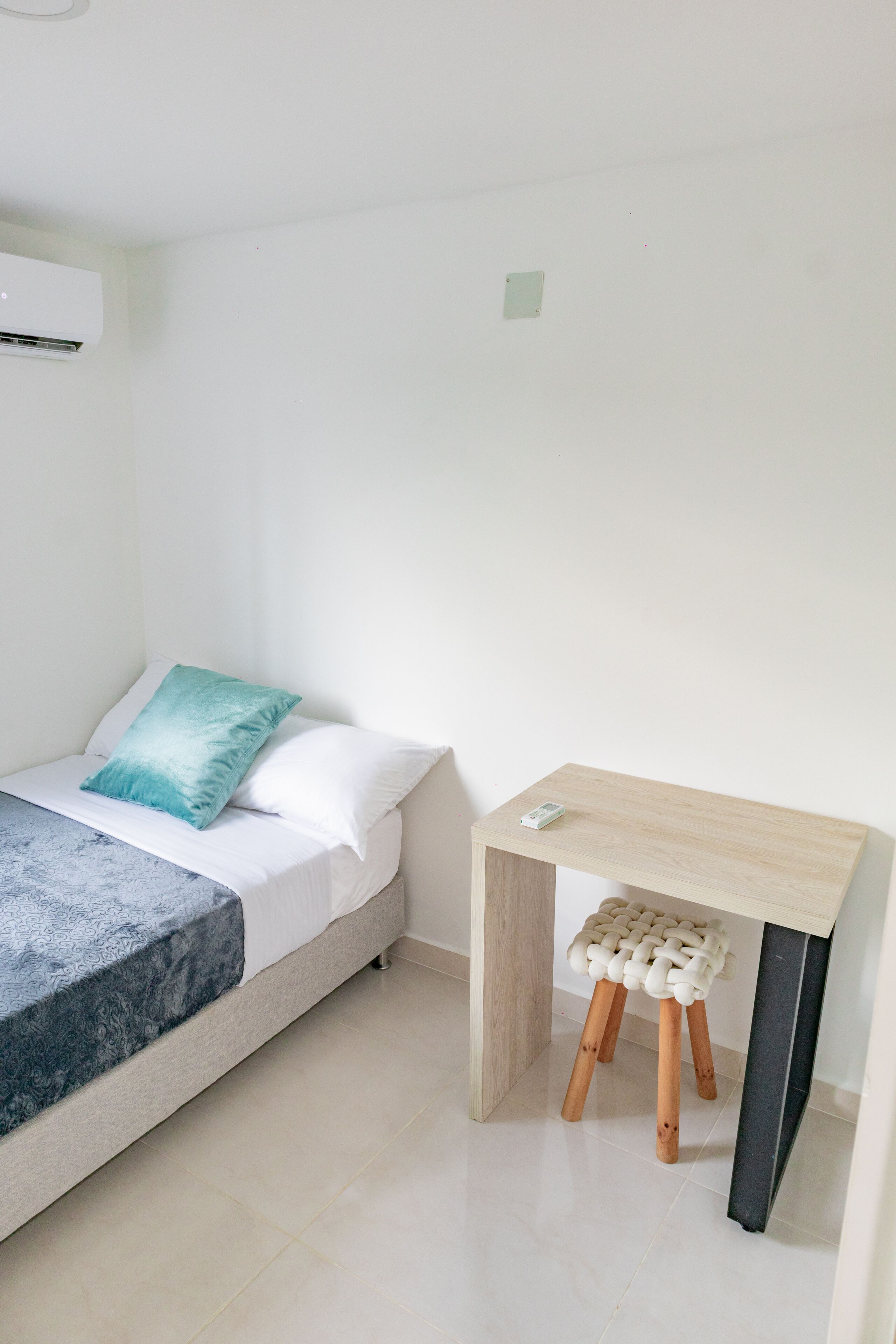 Una camera da letto con un letto, un comodino e uno sgabello.