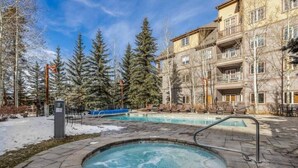 A hotel with a hot tub, outdoor pool, and snow-covered ground.