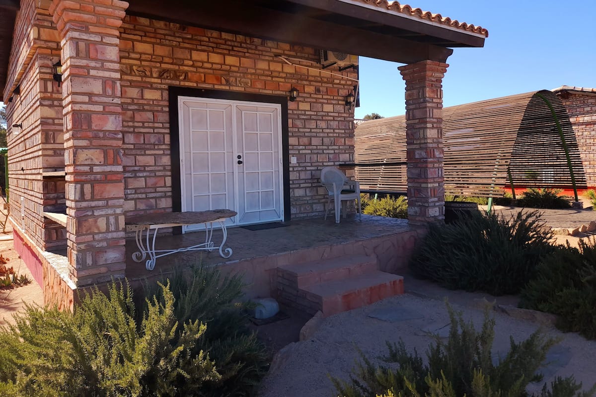 A brick building with a white door, a bench, and a covered patio area.