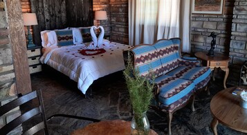 Una habitación acogedora con una cama, un sofá, una mesita y una planta decorativa.
