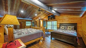 Ein gemütliches Schlafzimmer in einer Blockhütte mit zwei Betten, Holzbalkendecke und rustikalem Dekor.