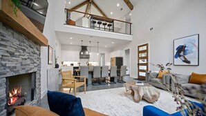 Un salón amplio con chimenea, zona de comedor y cocina al fondo.