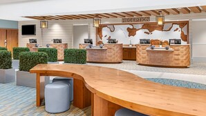 Ein Empfangsbereich mit einem Holzbüro, einem großen, gebogenen Tisch und einem wandmontierten Fernseher.