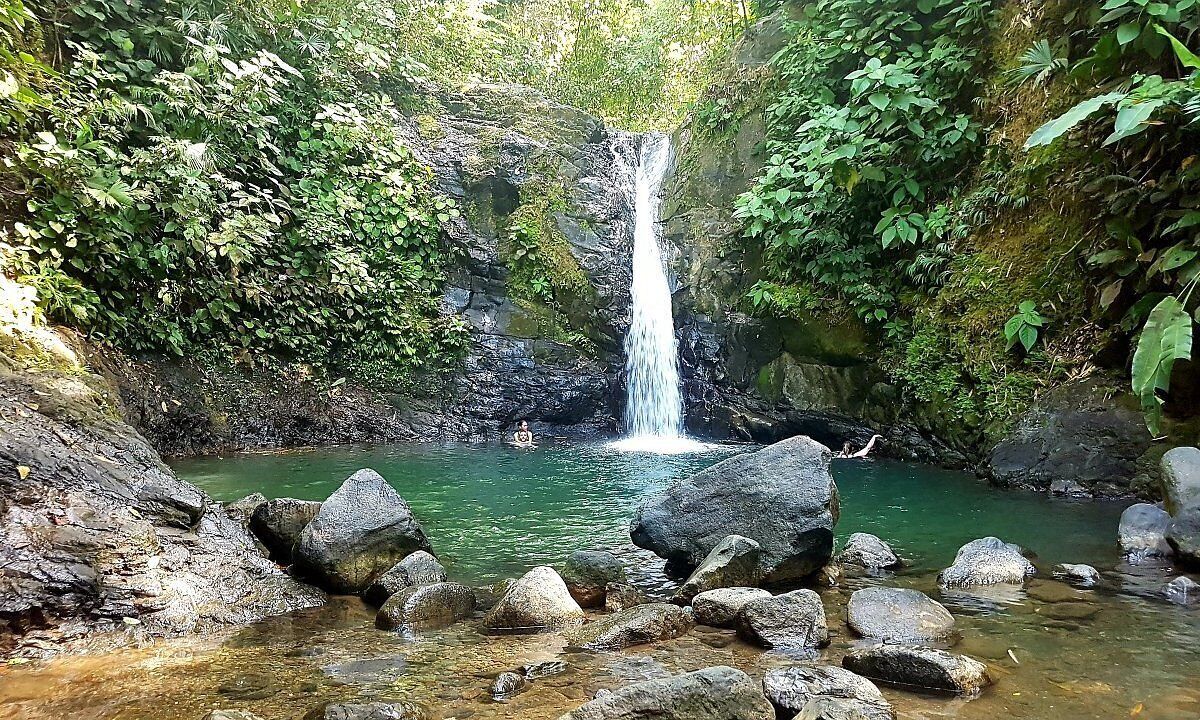 A waterfall in a natural setting with rocks and greenery.