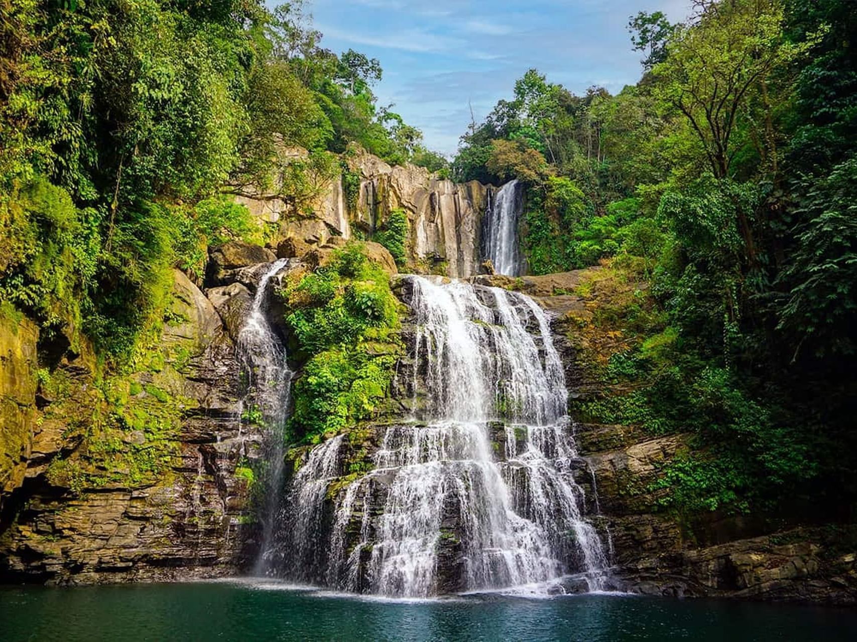 Una cascata a più livelli circondata da una vegetazione lussureggiante.