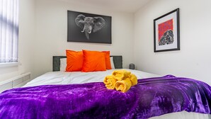 A hotel room with a bed, orange pillows, a purple blanket, and artwork on the walls. - Birmingham Apt-sleeps 4-walk to City Centre-pets (Birmingham)