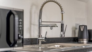 A modern kitchen with a stainless steel faucet, a coffee maker, and a microwave. - Birmingham Apt-sleeps 4-walk to City Centre-pets (Birmingham)