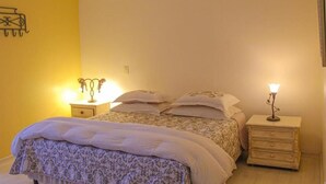 A bedroom with a bed, two bedside tables, and a wall-mounted light fixture. - Pousada Casa Gialla - Campos do Jordão (Campos do Jordão)