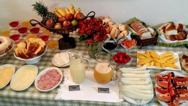 A table with various food items and drinks, including fruits, pastries, and a pitcher of lemonade. - Pousada Casa Gialla - Campos do Jordão (Campos do Jordão)