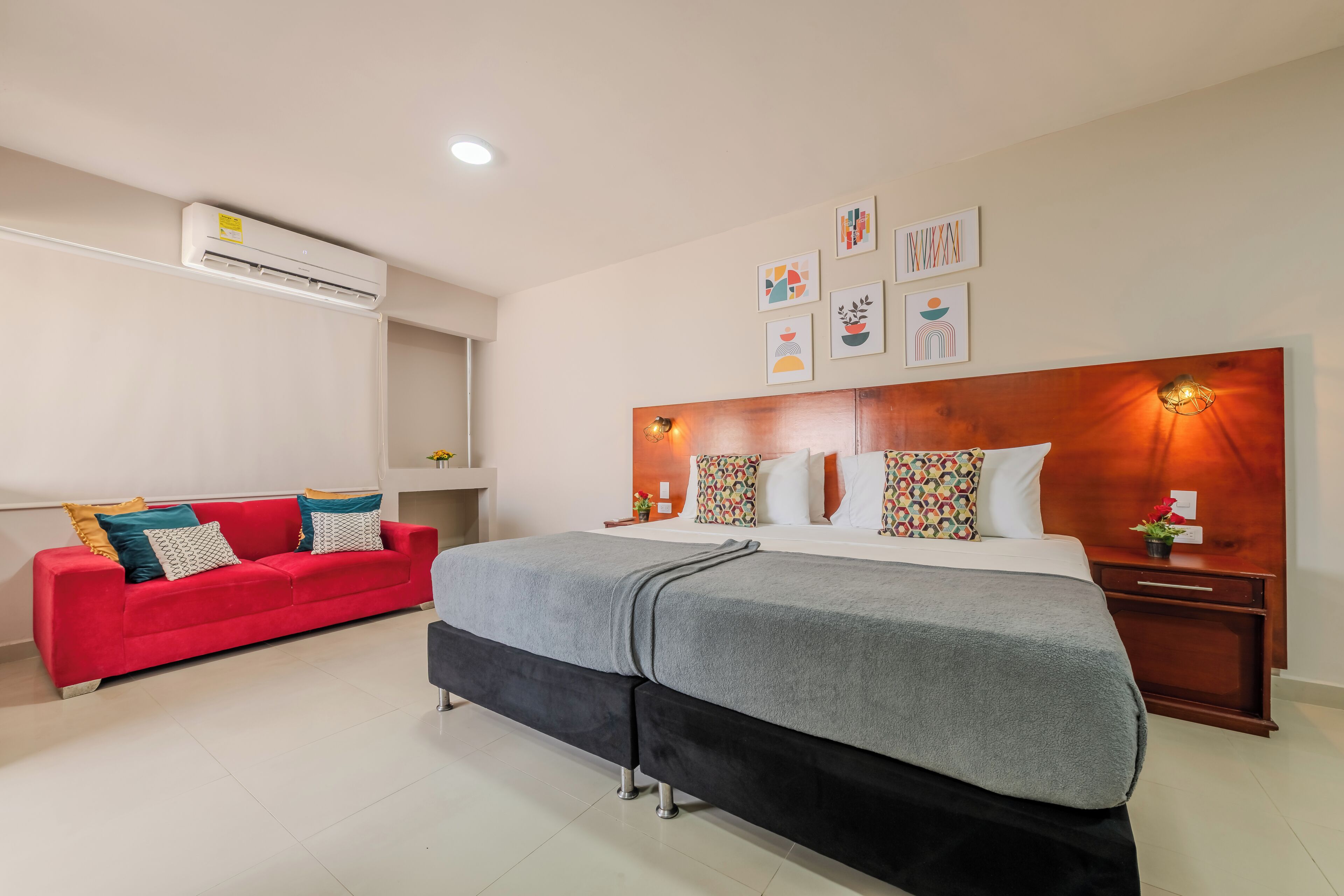 Una habitación de hotel con una cama, un sofá rojo, un cabecero de madera y decoración en la pared.