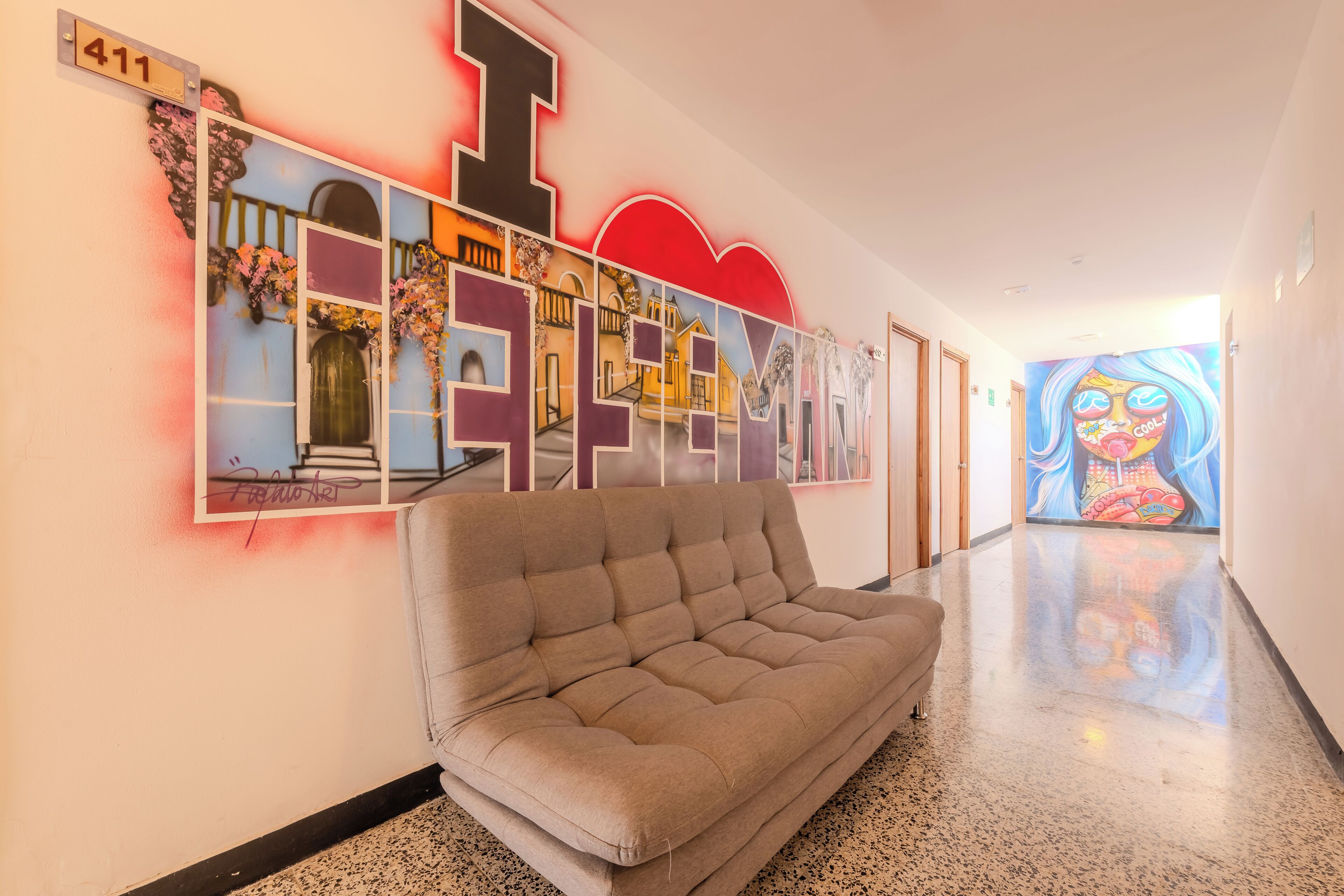 A hallway with a sofa, a large number sign, and a colorful mural on the wall.