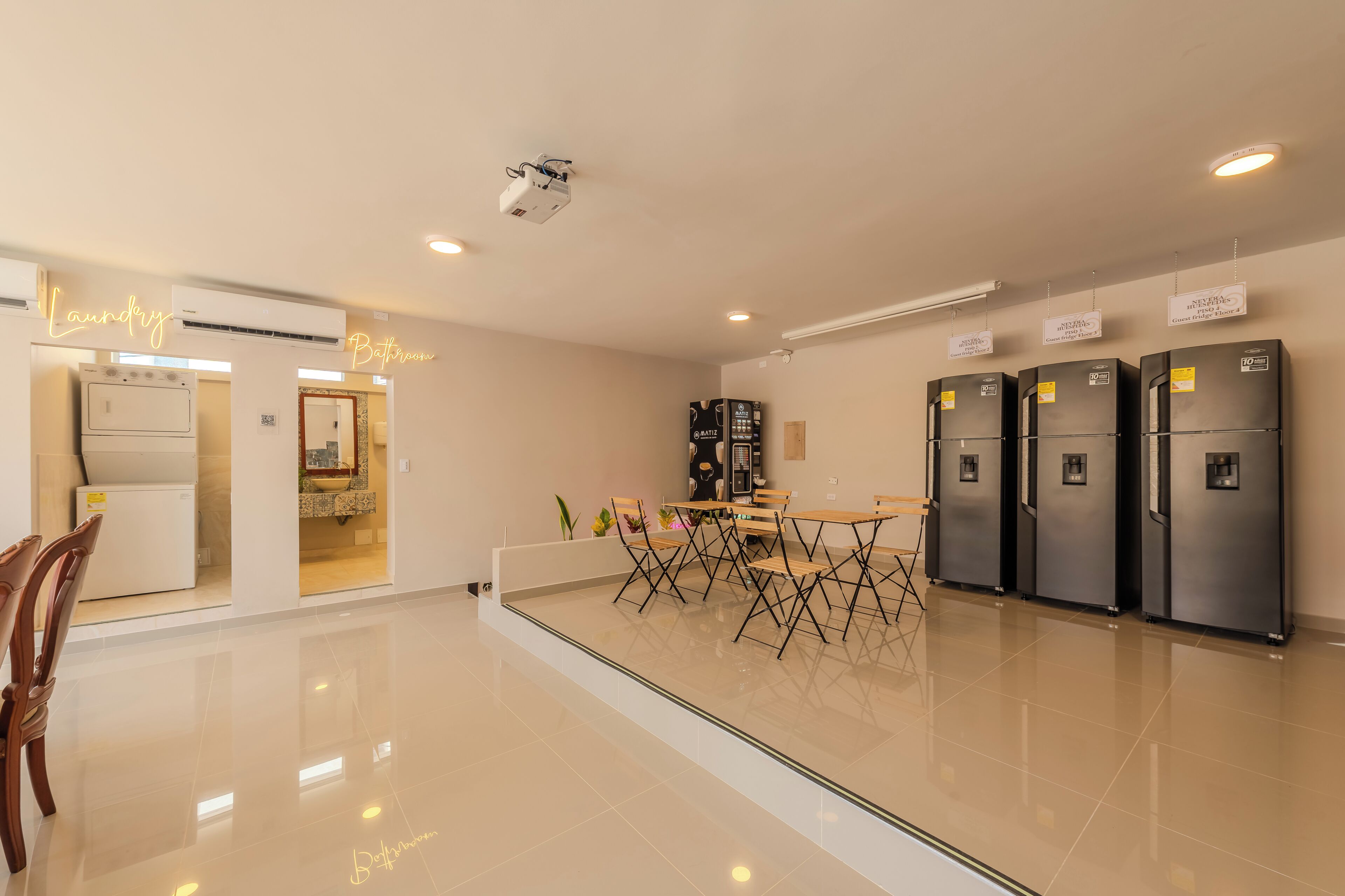 A modern hotel lobby with a glass partition, a dining area, and a kitchen area.