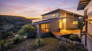 Une maison moderne avec une façade en bois, de grandes fenêtres et une terrasse en bois.