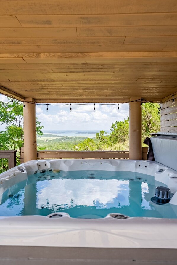 A hot tub under a wooden pergola with a scenic view.