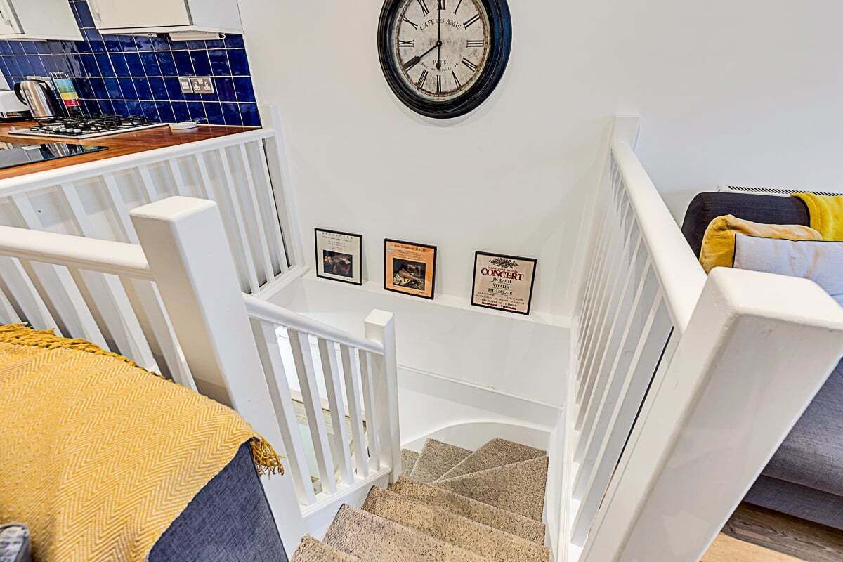 A staircase with white railings leading to a landing with framed certificates.