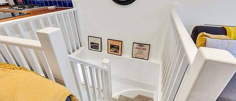 A staircase with white railings leading to a landing with framed certificates.