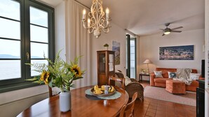 Ein Essbereich mit einem Holztisch, einem Blumenstrauß und Meerblick durch große Fenster.