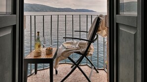Ein Balkon mit Tisch, Stuhl und einer Weinflasche.