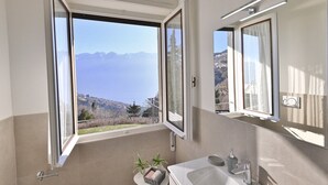 Un baño con un ventanal grande, un lavamanos y un espejo.