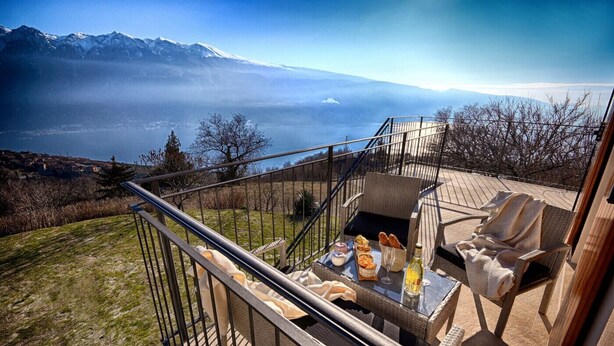 Un balcón con una mesa dispuesta para una comida, con vistas a un paisaje montañoso.