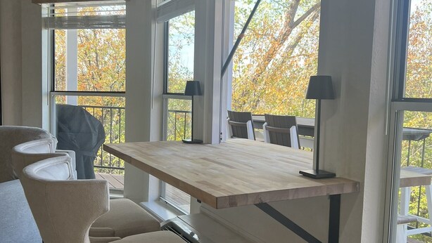 Une cuisine moderne avec une table en bois, un banc intégré et de grandes fenêtres donnant sur la forêt.
