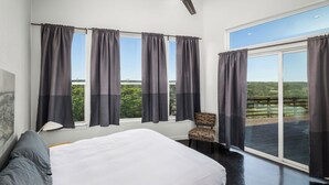 Ein Schlafzimmer mit einem großen Bett, einem Deckenventilator und Blick auf eine grüne Landschaft durch das Fenster.