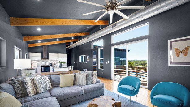 Ein modernes Wohnzimmer mit einem grauen Sofa, blauen Sesseln und einem Holztisch.