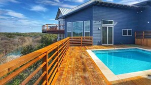Ein modernes Haus mit einer Holzterrasse und einem Swimmingpool.