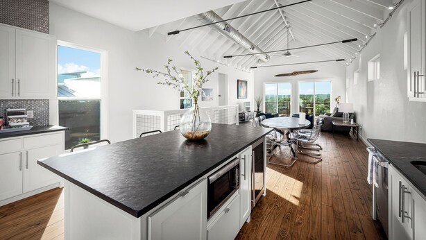 A modern kitchen with a large island, white cabinetry, and a view of the outdoors.