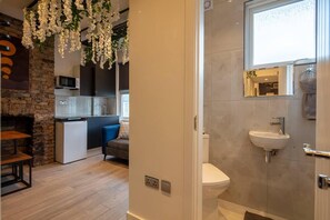 Experience a harmonious blend of rustic and contemporary design in this inviting space, featuring a stone wall, plush sofa, and elegant sink.