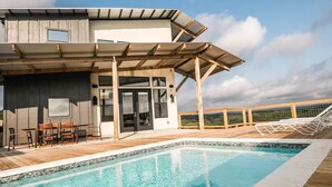 Un bâtiment moderne doté d’une piscine, d’une terrasse en bois et d’un espace salon extérieur.