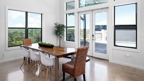 Une pièce spacieuse avec un plafond haut, de grandes fenêtres et un coin repas comprenant une table et des chaises.