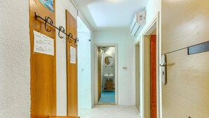Un pasillo con un banco de madera, una puerta con manija metálica y un equipo de aire acondicionado instalado en la pared.