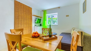 Un comedor con una mesa de madera, sillas, una botella y una bandeja con naranjas.