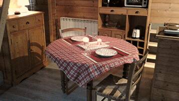 A wooden dining table with a checkered tablecloth, surrounded by wooden chairs.