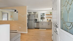 Una cocina moderna con electrodomésticos de acero inoxidable, horno empotrado y ventana con vistas a árboles.