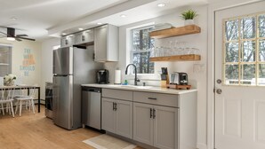 Una cocina moderna con electrodomésticos de acero inoxidable, armarios grises y una ventana con vista a árboles.