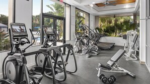 A gym with various exercise machines, a bench, and dumbbells. - Peaceful 2BR Villa at Marriott Sabal Palms – Full Kitchen + Quiet Resort Setting (Orlando)