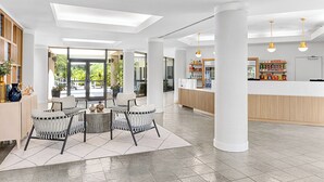 A spacious lobby with a seating area, a reception desk, and large windows offering a view of the outdoors. - Peaceful 2BR Villa at Marriott Sabal Palms – Full Kitchen + Quiet Resort Setting (Orlando)