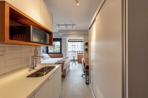 Una cocina moderna con microondas integrado, un lavabo y ventanal con vistas a la ciudad.