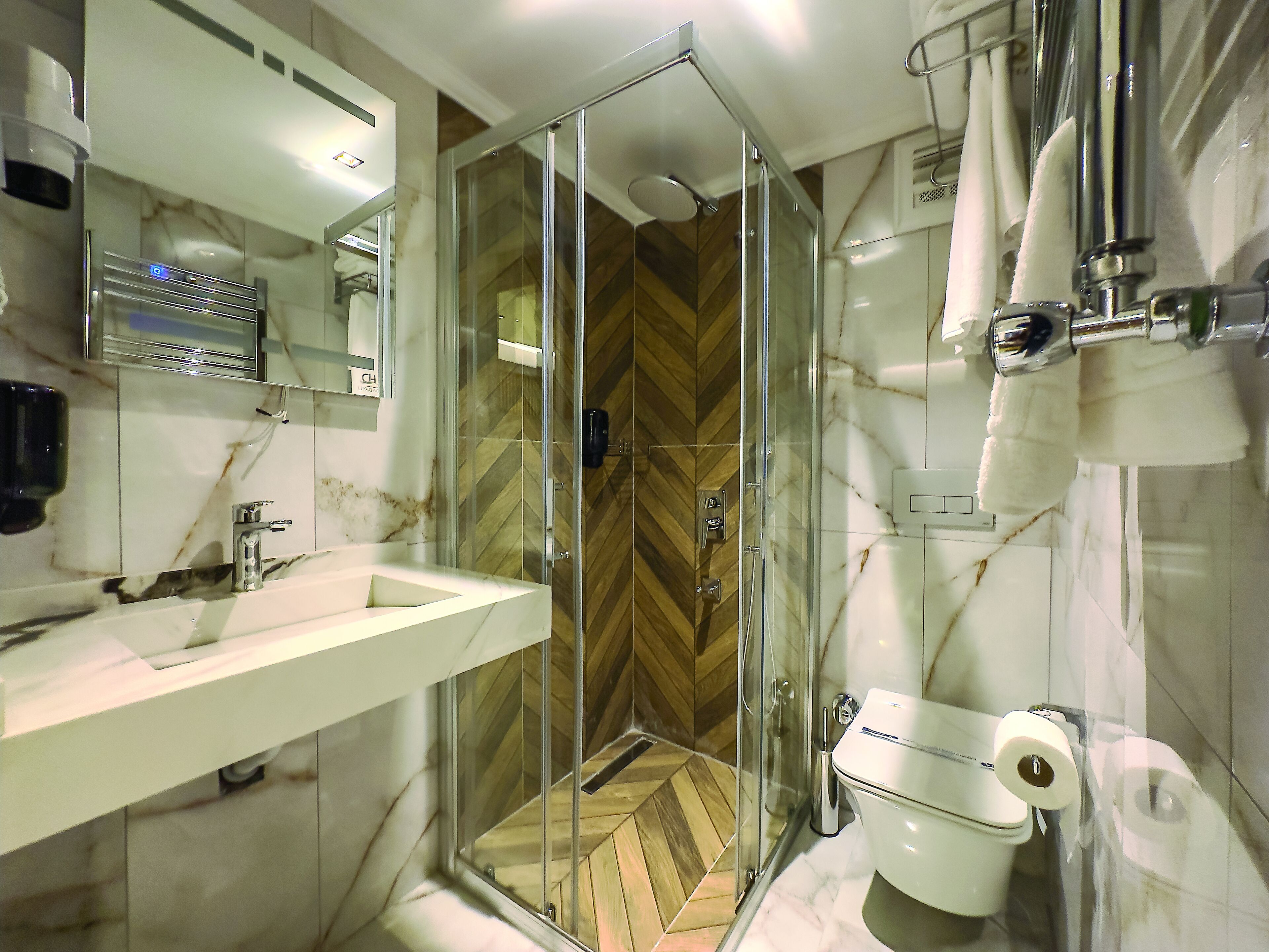 Un bagno moderno con cabina doccia in vetro, lavabo in marmo e un water.
