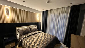 Une chambre à coucher moderne avec un lit, des tables de chevet et une grande fenêtre avec des rideaux.
