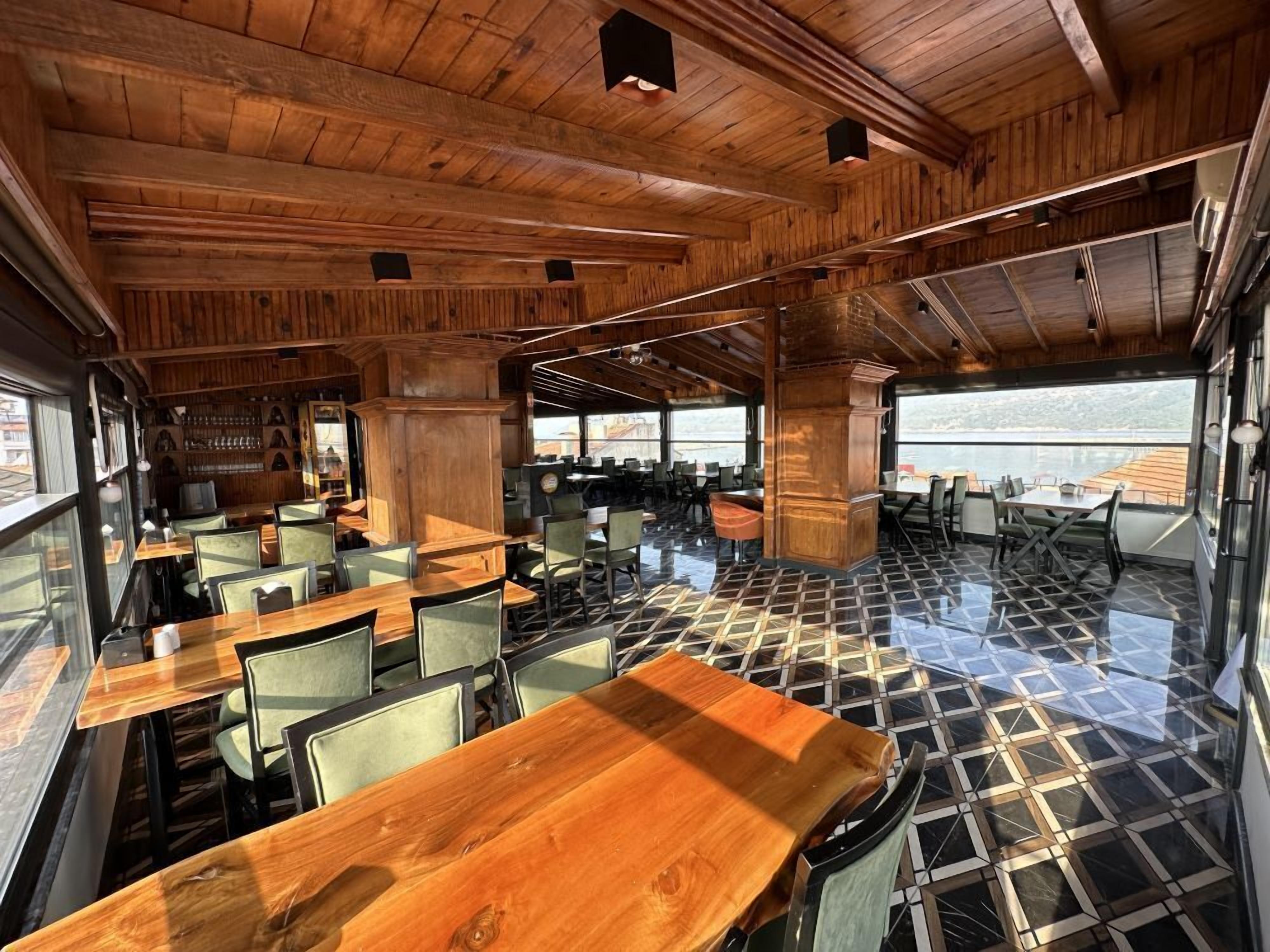 Un restaurante con interior de madera, ventanas amplias y suelo de baldosas.