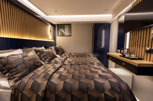 Un dormitorio moderno con una cama grande, una mesita de noche con hervidor y un espejo.