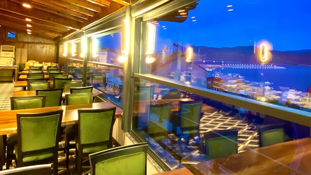 Un restaurant à l’intérieur en bois, doté de grandes fenêtres offrant une vue panoramique.