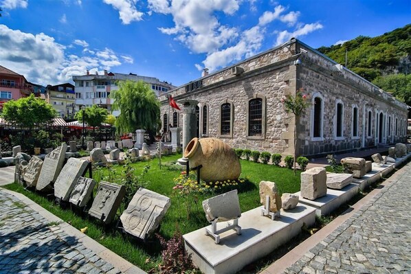 A stone building with arched windows and a flagpole. - Amasra Dadaylı Otel  (Amasra)