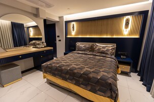 Un dormitorio moderno con una cama grande, un tocador con espejo y una mesita de noche con lámpara.