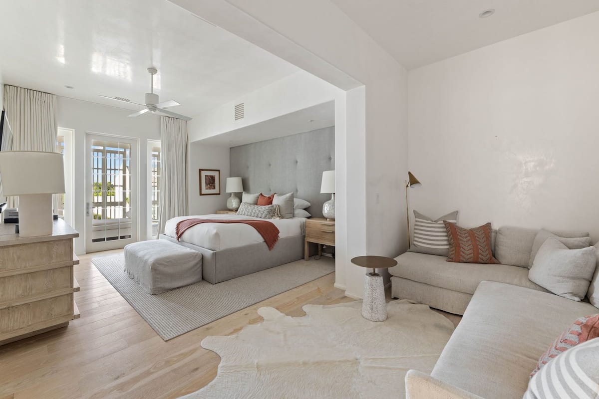 Un dormitorio amplio con una cama grande, una zona de estar con sofá, una mesita pequeña y una mesita de noche.