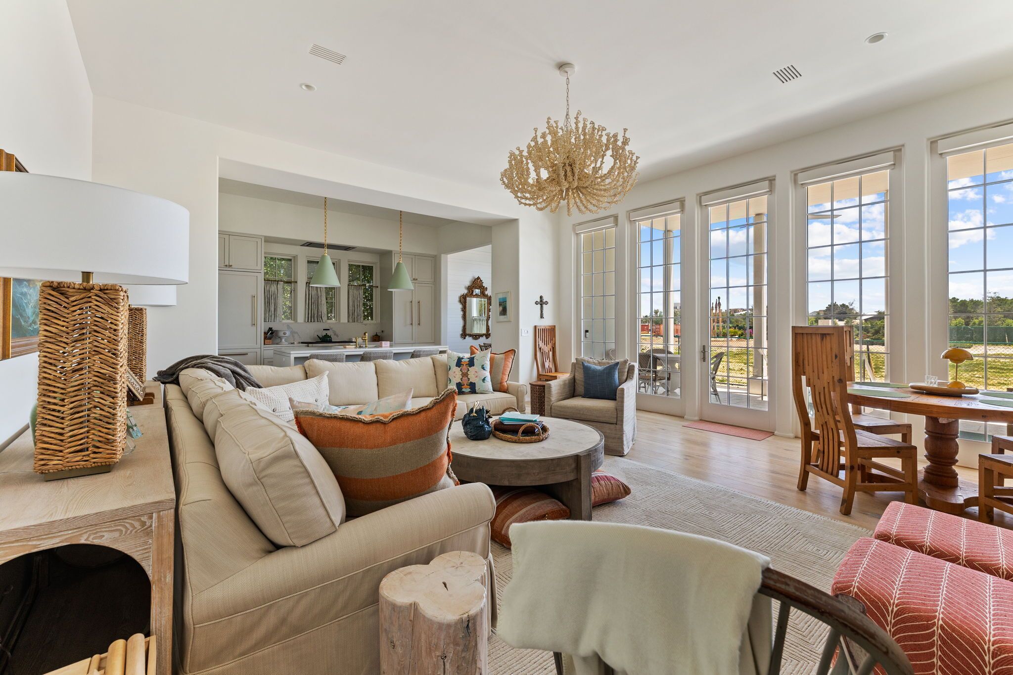 A spacious living room with a large sofa, a dining table, and a view of the outdoors through large windows.