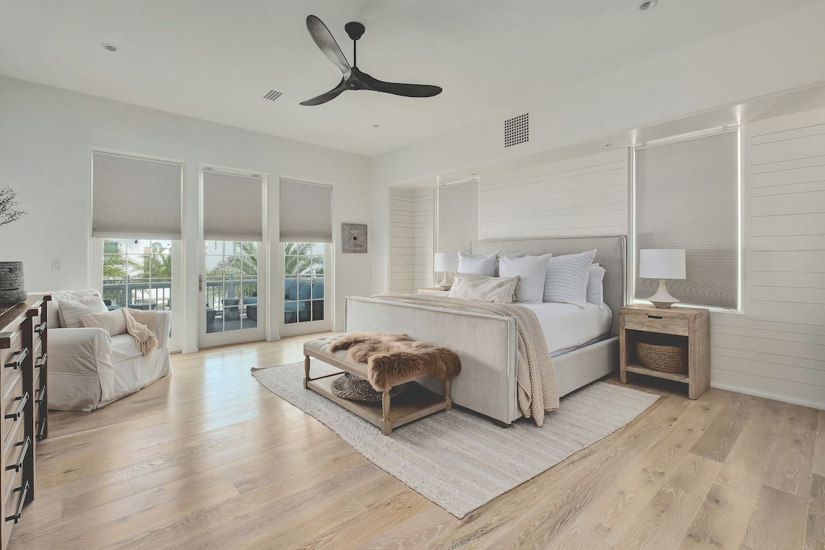 Un dormitorio amplio con una cama grande, un ventilador de techo y vistas a través de puertas de cristal.